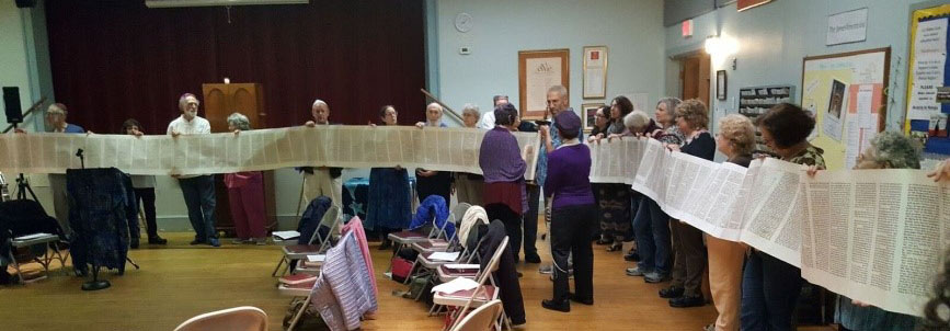 members of a synagogue holding an unrolled Torah scroll during a Simchat Torah celebration
